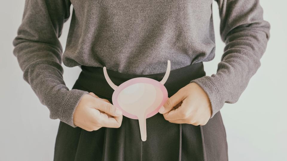 Woman holding a bladder cut out around her abdomen for Bladder Cancer Awareness Month. (Photo via Getty Images)