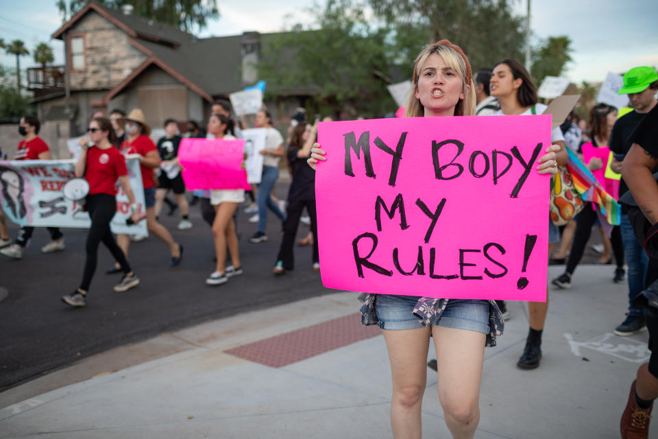 A woman holds a sign that says My Body My Rules!