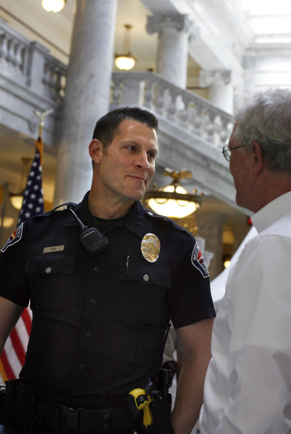 In this May 30, 2012, photo, Officer Kevin Peck of the West Valley Police Department, is congratulated after receiving the Law Enforcement Humanitarian Award at an awards ceremony honoring Utah's emergency responders at the Utah state Capitol, Salt Lake City. Peck was honored for calming and holding hands with a woman who was pinned underneath a UTA bus after getting hit while walking in a crosswalk in December 2011. The Deseret News reported that Peck helped save another crash victim while he was in Europe in November 2019. (Laura Seitz/The Deseret News via AP)