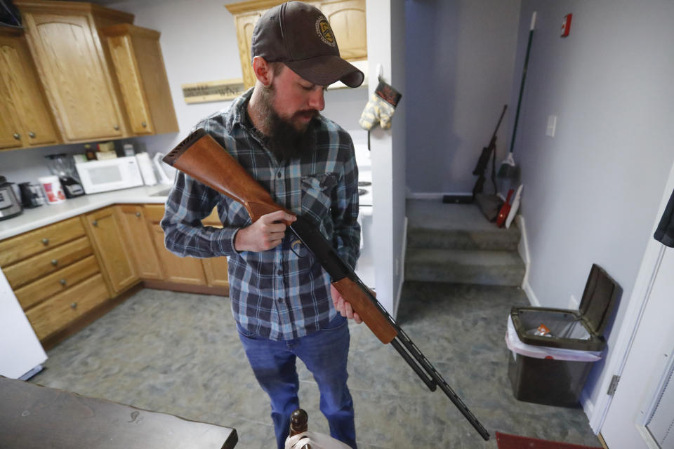 In this Friday, March 13, 2020, photo, Nic Talbott checks his pump shotgun at his home in Lisbon, Ohio. Talbott is a plaintiff in one of four lawsuits filed in federal courts challenging a Trump administration policy barring transgender Americans from enlisting in the military. (AP Photo/Keith Srakocic)