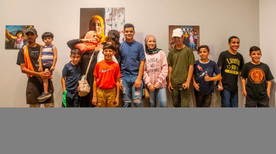 Single mother Zahra from Syria, along with her children, stands in front of an image of her that is on display in the “Where We Belong: Refugee Stories from Wichita” exhibition at the Ulrich Museum of Art on the Wichita State campus. The Syrian family is one of five refugee families featured in the exhibition.