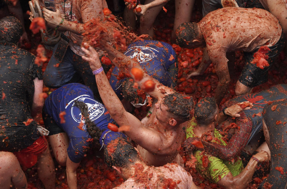 Revellers throw tomatoes at each other during the annual “Tomatina”, tomato fight fiesta, in the village of Bunol near Valencia, Spain, Wednesday, Aug. 30, 2023. Thousands gather in this eastern Spanish town for the annual street tomato battle that leaves the streets and participants drenched in red pulp from 120,000 kilos of tomatoes. (AP Photo/Alberto Saiz)