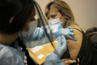 Nurse Carolina administers a booster shot of the Pfizer vaccine against COVID-19 to a fellow nurse on the first day of a new vaccination center in Lisbon, Wednesday, Dec. 1, 2021. Long lines formed at the Portuguese capital's largest vaccination center to date as authorities there tried to encourage the 2% of the population who are not vaccinated yet, Europe's lowest rate, and to speed up the administration of booster shots. (AP Photo/Armando Franca)