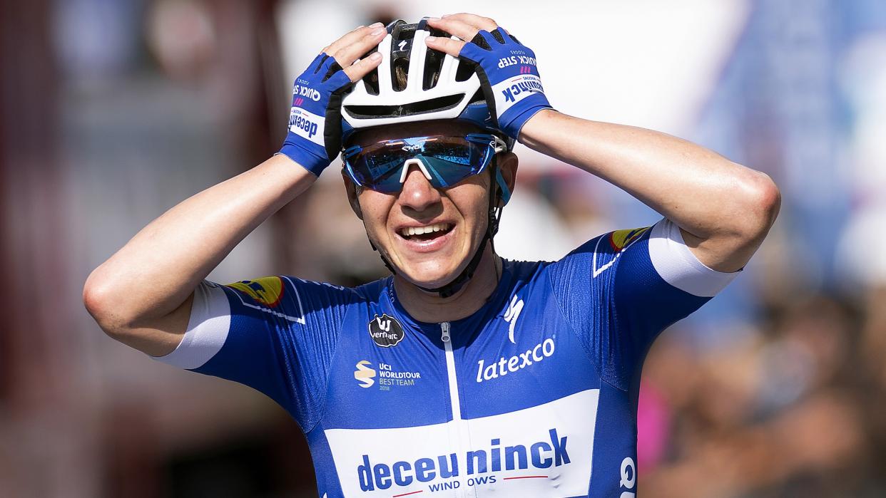  Remco Evenepoel of Belgium in cycling helmet and sunglasses holds his hands up in celebration 