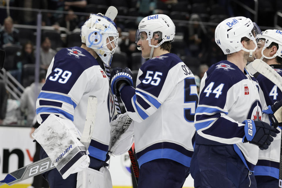 Winnipeg Jets center Mark Scheifele (55) congratulates goaltender Laurent Brossoit (39) as defenseman Josh Morrissey (44) skates away after the 3-0 win over the Seattle Kraken in an NHL hockey game, Friday, March 8, 2024, in Seattle. AP Photo/John Froschauer)