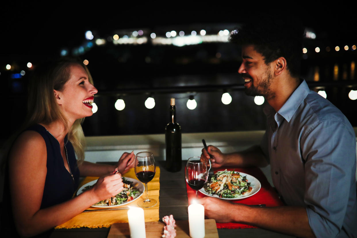 Young beautiful couple in love having romantic dinner at night on rooftop