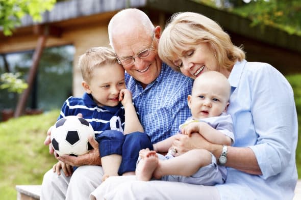 Portrait of happy grandparents with their grandchildren sitting outdoors