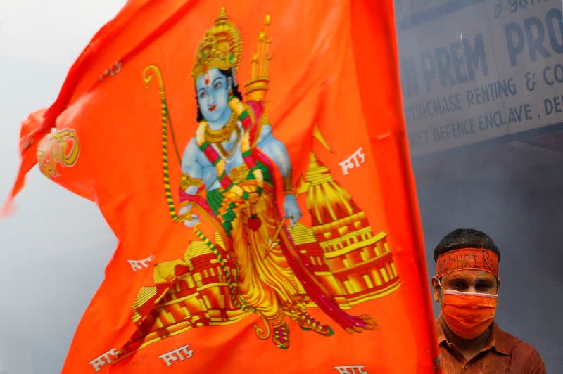 A man stands near a flag during a live screening of the stone laying ceremony of the Ram Temple by Prime Minister Narendra Modi in Ayodhya, in New Delhi