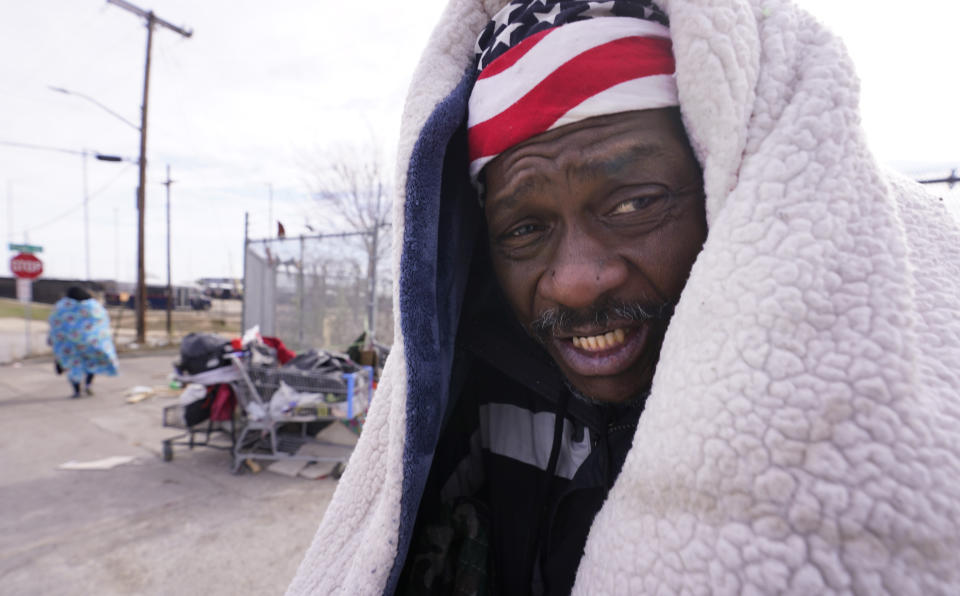 Kevin Hall uses a blanket to keep warm from freezing temperatures while standing on the street in Fort Worth, Texas, Friday, Dec. 23, 2022. (AP Photo/LM Otero)