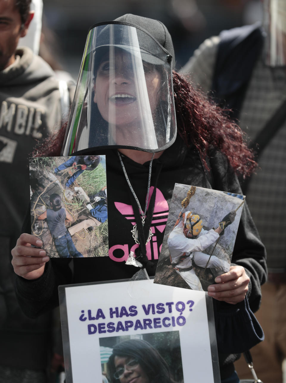 A woman wearing a mask amid the new coronavirus pandemic holds an image of a person who was disappeared, during a protest in front of the National Palace in Mexico City, Thursday, June 4, 2020. Relatives of different groups searching for the disappeared protested the cut to the budget destined for their search. (AP Photo/Eduardo Verdugo)