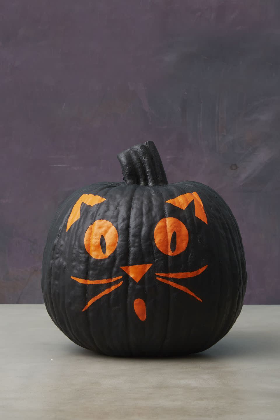 <p>Mask out the eyes, mouth, nose, ears, (and whiskers!) on an orange pumpkin with blue <a href="https://www.amazon.com/ScotchBlue-Painters-Multi-Use-1-88-Inch-60-Yard/dp/B00004Z4DU/?tag=syn-yahoo-20&ascsubtag=%5Bartid%7C10055.g.1714%5Bsrc%7Cyahoo-us" rel="nofollow noopener" target="_blank" data-ylk="slk:painter's tape;elm:context_link;itc:0;sec:content-canvas" class="link ">painter's tape</a>. Cover the rest with <a href="https://www.amazon.com/Apple-Barrel-J20404-Acrylic-Assorted/dp/B0018NBUPC/?tag=syn-yahoo-20&ascsubtag=%5Bartid%7C10055.g.1714%5Bsrc%7Cyahoo-us" rel="nofollow noopener" target="_blank" data-ylk="slk:black acrylic paint;elm:context_link;itc:0;sec:content-canvas" class="link ">black acrylic paint</a>. Let dry, then remove the tape to reveal.</p><p><a class="link " href="https://www.amazon.com/DecoArt-DCA47-9-Crafters-Acrylic-8-Ounce/dp/B001C2EYT8/?tag=syn-yahoo-20&ascsubtag=%5Bartid%7C10055.g.1714%5Bsrc%7Cyahoo-us" rel="nofollow noopener" target="_blank" data-ylk="slk:SHOP PAINT;elm:context_link;itc:0;sec:content-canvas">SHOP PAINT</a><br></p>