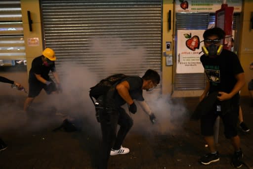 Pro-democracy protesters pour water on tear-gas shells fired by police in the Sham Shui Po area of Hong Kong