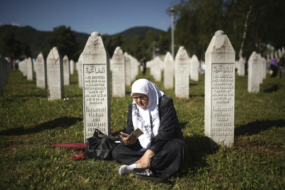 A Bosnian muslim woman prays at a grave in Memorial Centre in Potocari, Monday, July 11, 2022. Thousands converge on the eastern Bosnian town of Srebrenica to commemorate the 27th anniversary on Monday of Europe's only acknowledged genocide since World War II. (AP Photo/Armin Durgut)