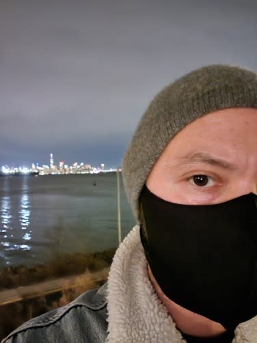 Man wearing face mask at night while taking selfie.