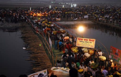 Indian Hindu devotees cross a bamboo bridge as they gather to pay homage to the setting sun during the Chhat Puja festival on the banks of the Ganges River in Patna. At least 18 women and children were killed and more than a dozen people seriously hurt in a stampede after the bridge collapsed