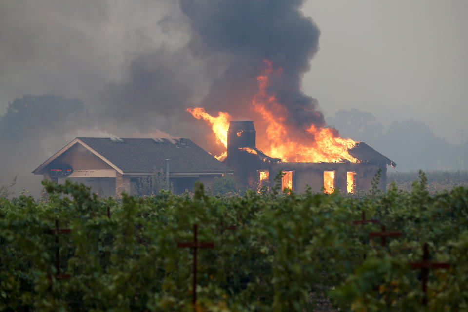 A burning structure is seen in the middle of a vineyard during the Kincade fire in Geyserville, California, U.S. October 24, 2019. REUTERS/Stephen Lam