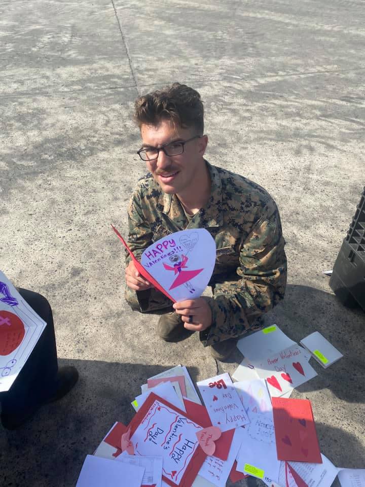 A service member at a California base holds up a valentine card sent by the Weymouth Rotary Club.