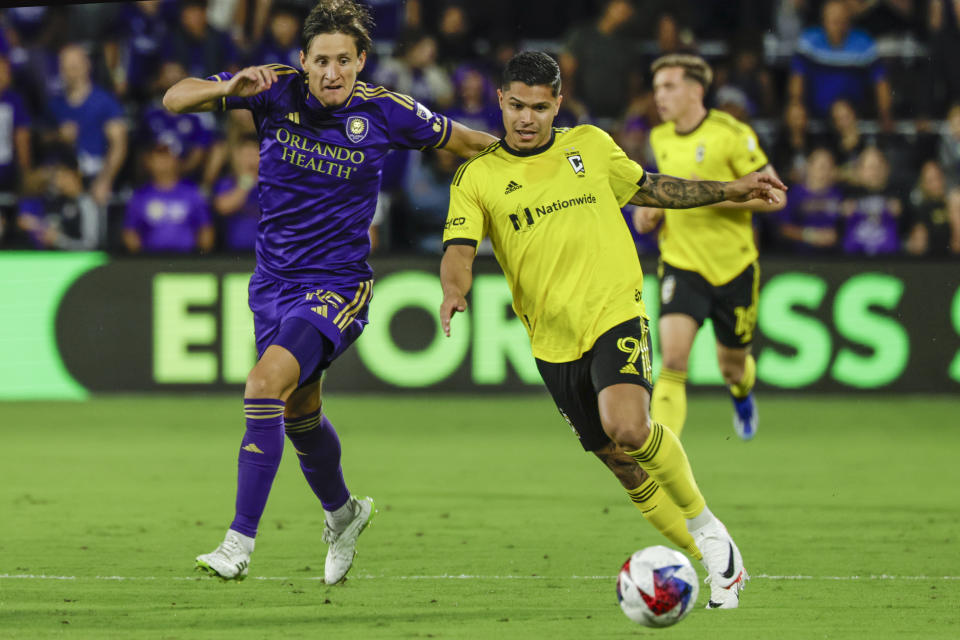 Columbus Crew forward Cucho Hernández, right, is defended by Orlando City defender Rodrigo Schlegel, left, during the first half of an MLS soccer playoff match, Saturday, Nov. 25, 2023, in Orlando, Fla. (AP Photo/Kevin Kolczynski)