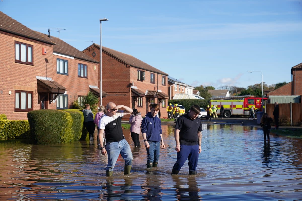 Residents walk through flood water in Retford in Nottinghamshire, after Storm Babet battered the UK (Joe Giddens/PA). (PA Wire)