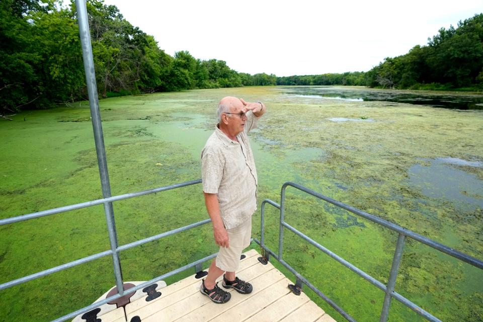 Bud Hammes, the chair of a community group called Friends of Trempealeau Lakes, stands on a pier surrounded by algae on Second Lake.