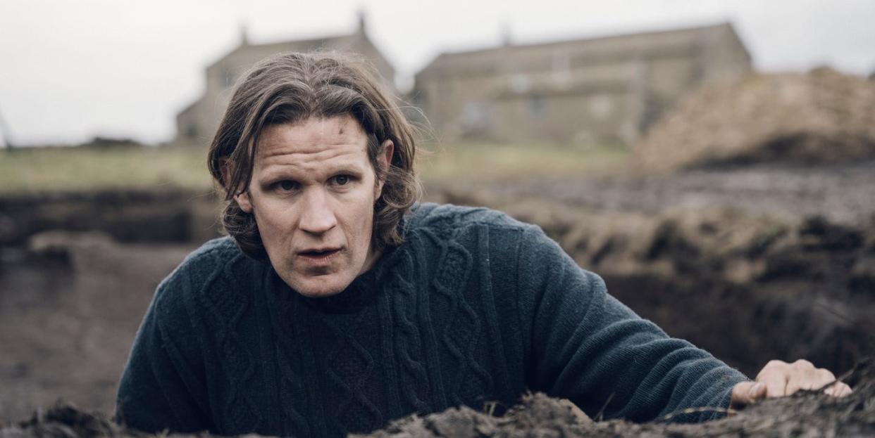 actor matt smith in jumper climbs out of large hole in field