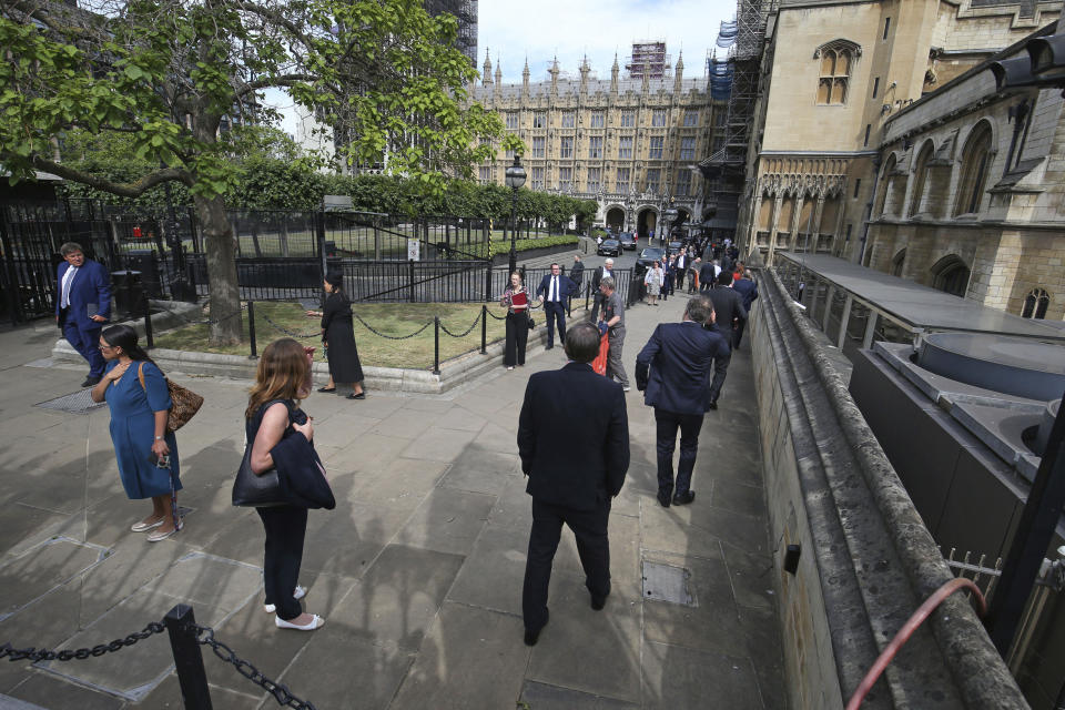 UK lawmakers queue outside the Houses of Commons in Westminster, London, Tuesday June 2, 2020. Prime Minister Boris Johnson's Conservative government faced a rebellion from some of its own legislators on Tuesday after it summoned Members of Parliament back to London and prepared to scrap a remote-voting system used during a nationwide coronavirus lockdown. (Jonathan Brady/PA via AP)