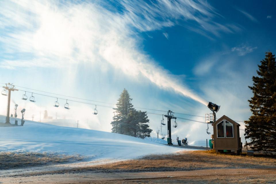 Mounted fan snow machines blow snow across Mount Brighton's ski slopes on Dec. 26, 2023.