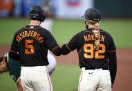 <p>First base coach Alyssa Nakken elbow bumps Mike Yastrzemski #5 of the San Francisco Giants after he walked in the third against the Oakland Athletics during their exhibition game at Oracle Park on July 21 in San Francisco.</p>