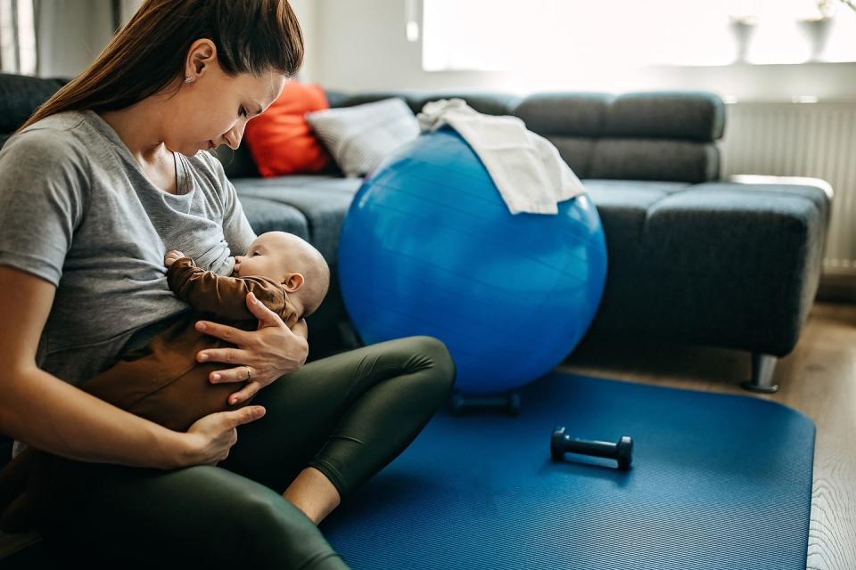 two people, mother taking a break from exercising to breastfeed her baby son at home