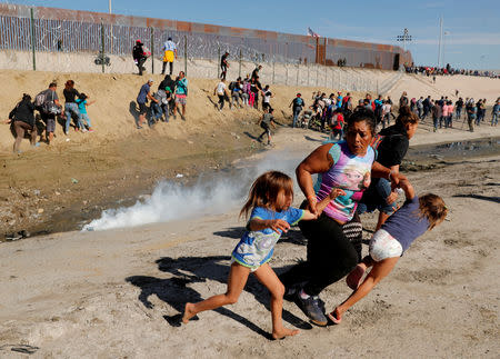 FILE PHOTO: Maria Meza (C), a 40-year-old migrant woman from Honduras, part of a caravan of thousands from Central America trying to reach the United States, runs away from tear gas with her five-year-old twin daughters Saira Mejia Meza (L) and Cheili Mejia Meza (R) in front of the border wall between the U.S and Mexico, in Tijuana, Mexico November 25, 2018. REUTERS/Kim Kyung-Hoon/File Photo