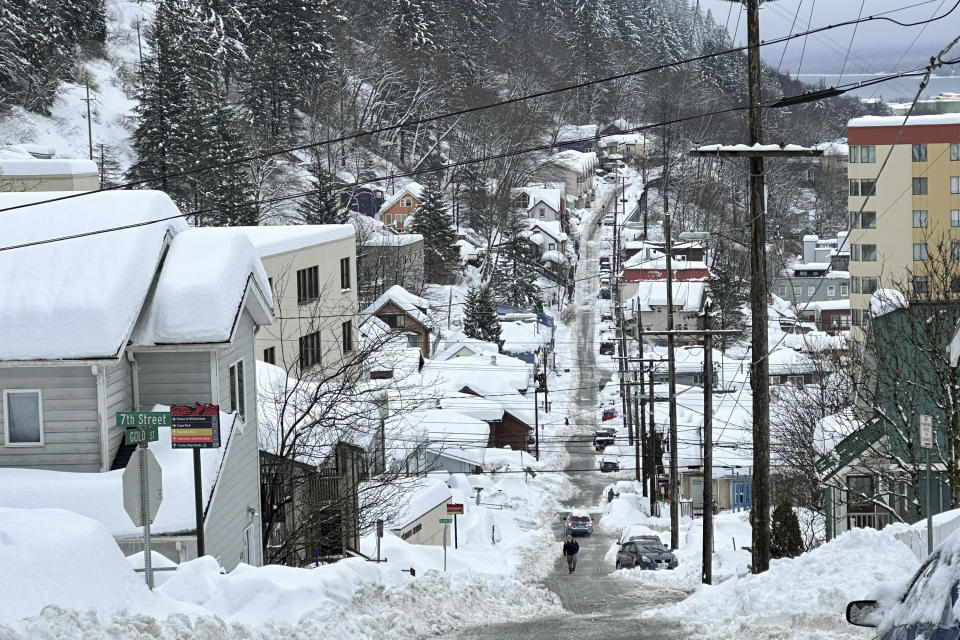 A pedestrian walks up a steep downtown street in Juneau, Alaska, on Wednesday, Jan. 24, 2024. The city was digging out from a snowstorm that helped bring its snowfall totals for the month of January to near-record levels. (AP Photo/Becky Bohrer)