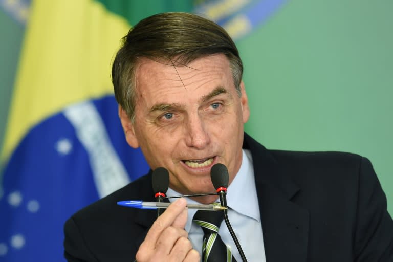 Brazilian President Jair Bolsonaro holds up his pen before signing a decree that makes it easier for adults with no criminal records to buy guns and keep them at home