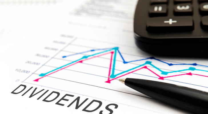 A photo of a paper with a chart and the word "Dividends" written on it, with a pen and calculator resting on top of it.