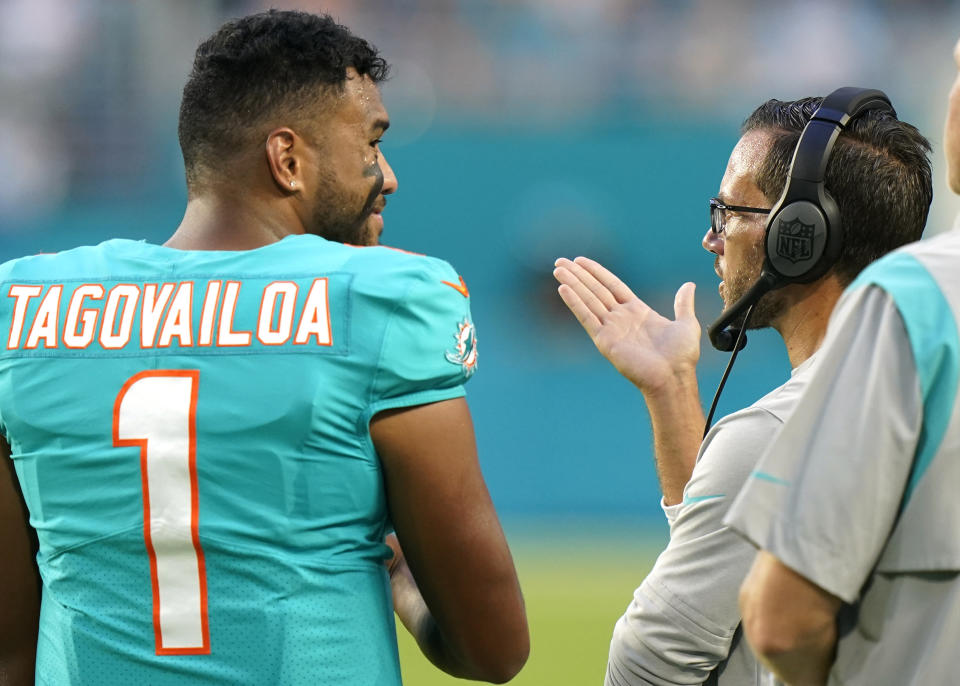 Miami Dolphins quarterback Tua Tagovailoa (1) talks with head coach Mike McDaniel during the first half of a NFL preseason football game against the Philadelphia Eagles, Saturday, Aug. 27, 2022, in Miami Gardens, Fla. (AP Photo/Wilfredo Lee)