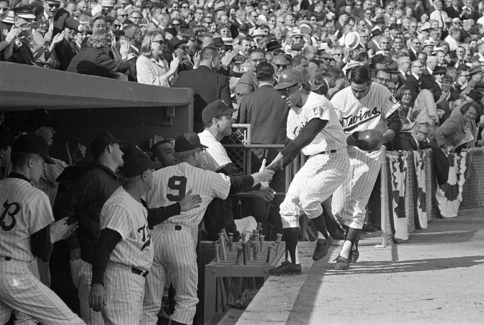 A baseball player greeted by teammates in a dugout