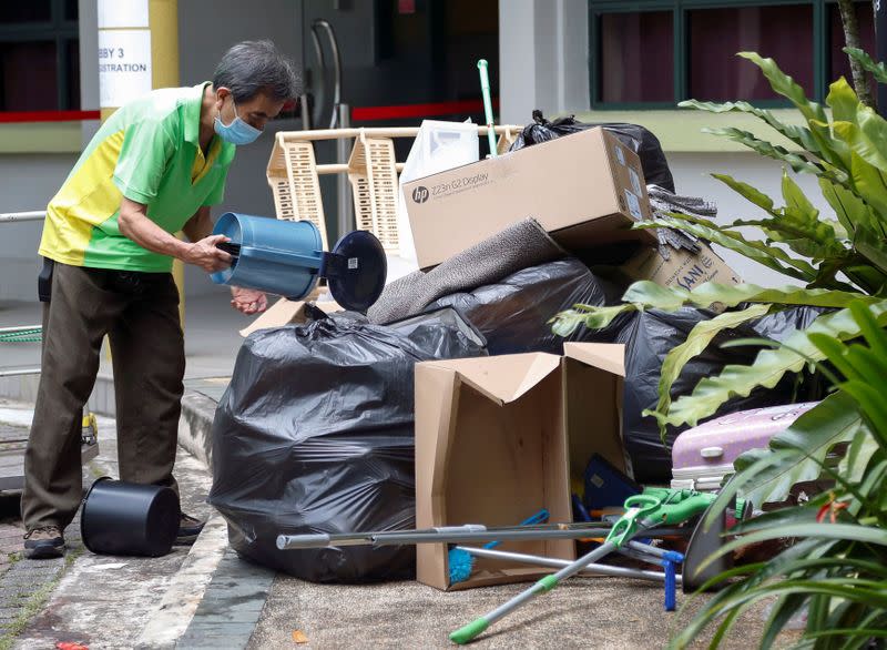 A worker clears rubbish in a dormitory area that is being used as a quarantine zone within Nanyang Technological University in Singapore