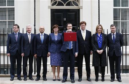 Britain's Chancellor of the Exchequer, George Osborne, holds up his budget case for the cameras as he stands with members of his Treasury team outside number 11 Downing Street, before delivering his budget to the House of Commons, in central London March 19, 2014. REUTERS/Suzanne Plunkett