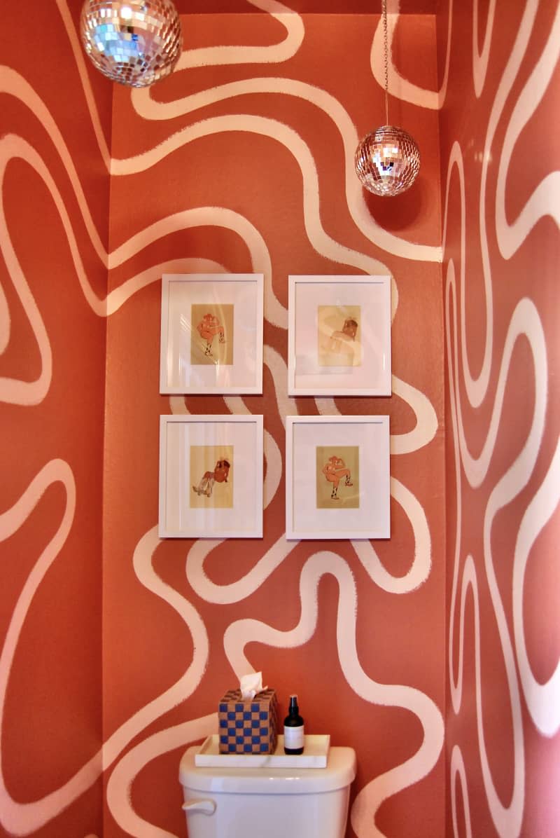 Colorful bathroom with squiggly motif on wall and disco balls hung from ceiling.