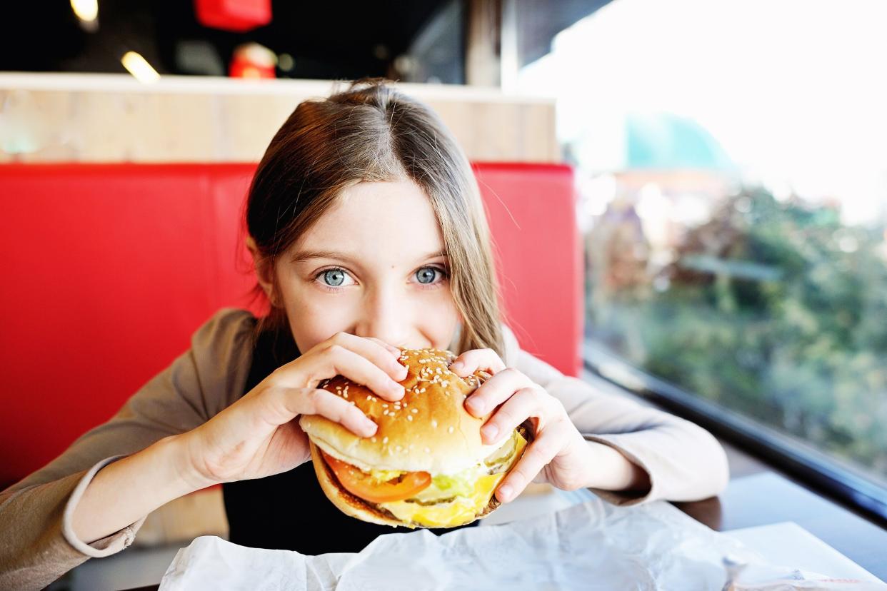 girl in school uniform eating a hamburger in the restaurant