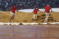 Fenway Park grounds crew pull a tarp into place on the infield during a rain delay in the fifth inning of a baseball game between the Boston Red Sox and the New York Yankees, Thursday, July 22, 2021, in Boston. (AP Photo/Elise Amendola)