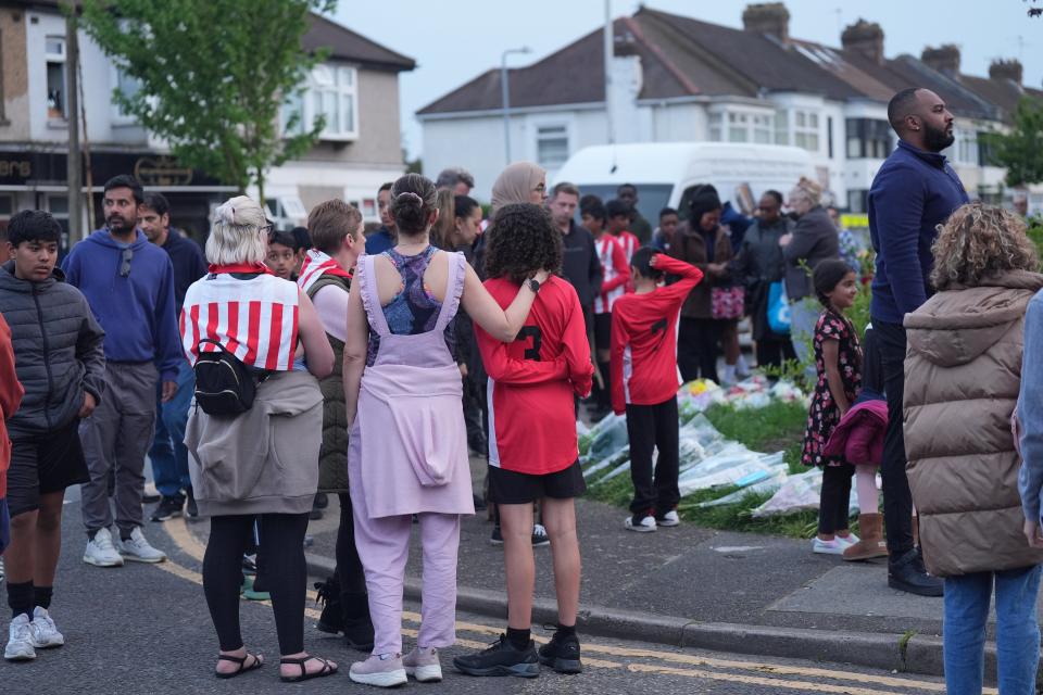 Members of the community, including River Hawks FC, looking at floral tributes in Hainault (Yui Mok/PA Wire)