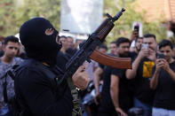 A man fires in the air during the funeral of three Hezbollah supporters who were killed during Thursday clashes, in the southern Beirut suburb of Dahiyeh, Lebanon, Friday, Oct. 15, 2021. The government called for a day of mourning following the armed clashes, in which gunmen used automatic weapons and rocket-propelled grenades on the streets of the capital, echoing the nation's darkest era of the 1975-90 civil war. (AP Photo/Bilal Hussein)