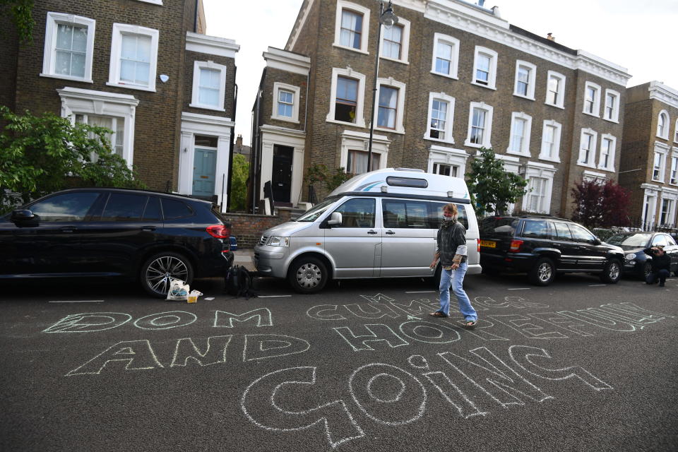 A protester writes out a message outside the north London home of Prime Minister Boris Johnson's senior aide Dominic Cummings , as lockdown questions continue to bombard the Government after it emerged that he travelled to his parents' home despite coronavirus-related restrictions.