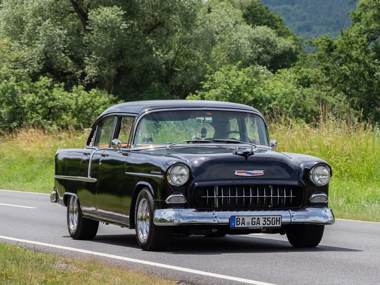 Black Chevrolet Bel Air 1955 driving on a summer day