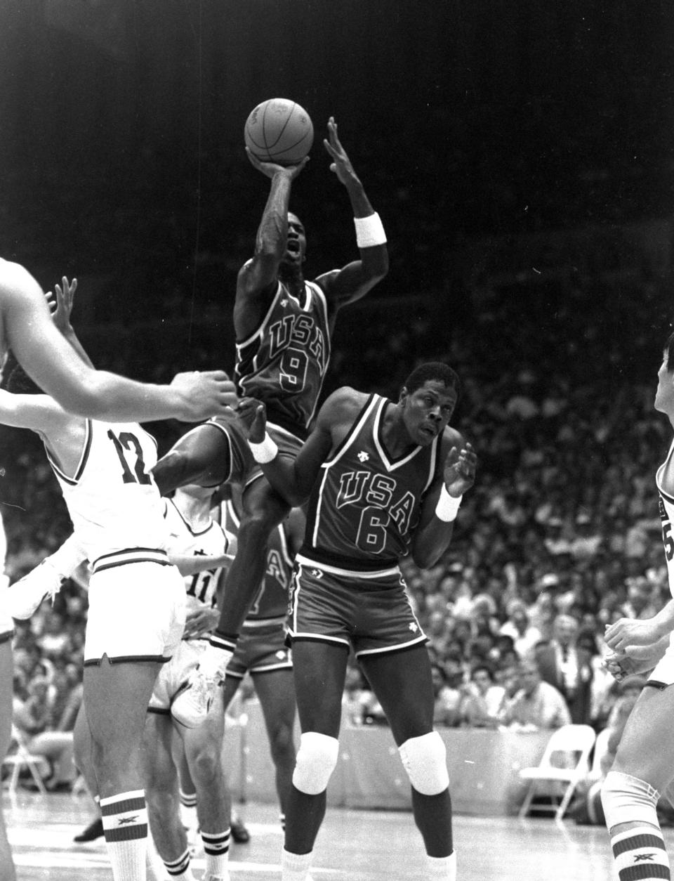 FILE - United States' Patrick Ewing (6) ducks as teammate Michael Jordan (9) goes up for a shot during Sunday night's Olympic basketball match against China at the Los Angeles Forum, July 29, 1984. Bob Knight built his best teams with a unique blend of talent and fit. It was never more evident than the 12-man roster he selected for the 1984 U.S. Olympic team. (AP Photo/Rusty Kennedy, File)
