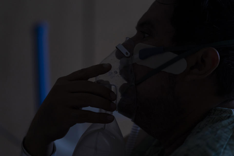 FILE - A COVID-19 patient, struggles to breathe while talking to a nurse at Providence Holy Cross Medical Center in Los Angeles, on Dec. 14, 2021. The explosive increase in U.S. coronavirus case counts is raising alarm, but some experts believe the focus should instead be on COVID-19 hospital admissions. And those aren't climbing as fast. (AP Photo/Jae C. Hong, File)