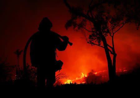 A firefighter is working on extinguishing the Lilac Fire, a fast moving wildfire in Bonsall, California, U.S., December 7, 2017. REUTERS/Mike Blake