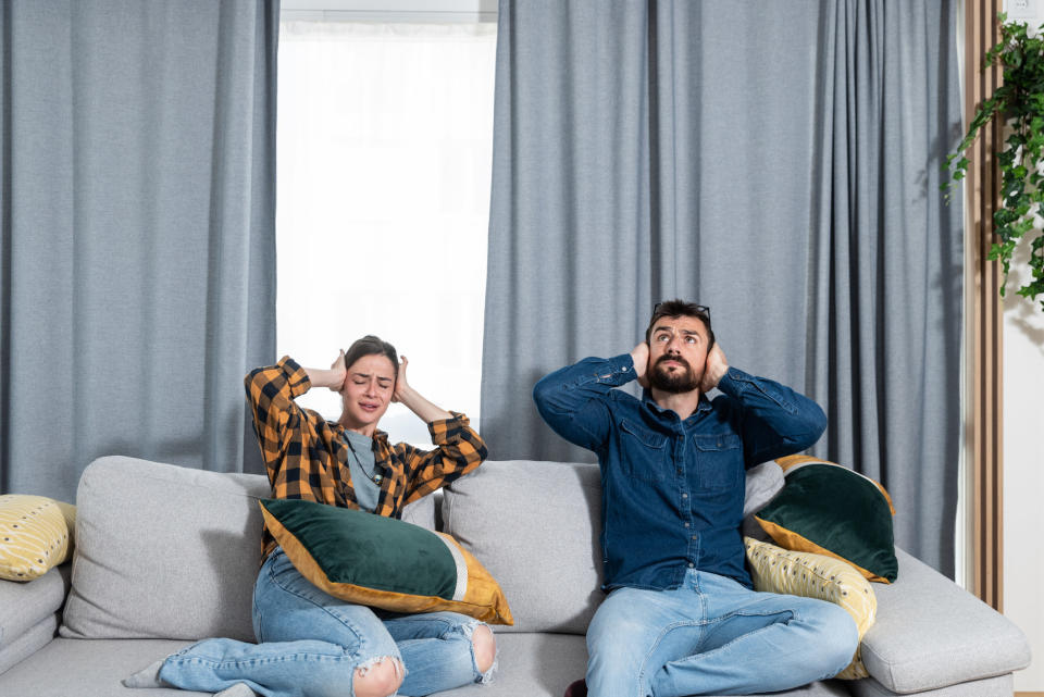 couple on the couch covering their ears