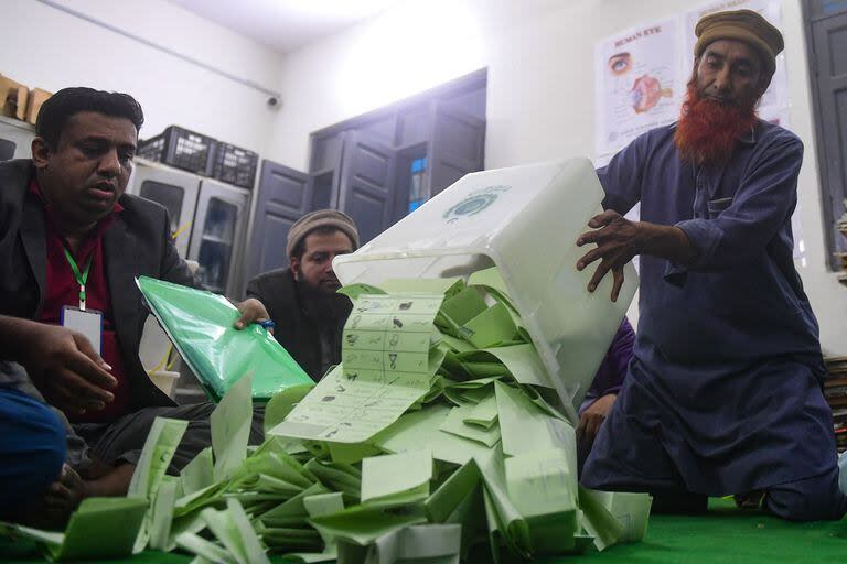 El personal electoral abre las urnas en presencia de agentes electorales de diversos partidos políticos cuando comienzan a contar los votos cuando terminan las elecciones nacionales en Karachi
(Asif HASSAN / AFP)