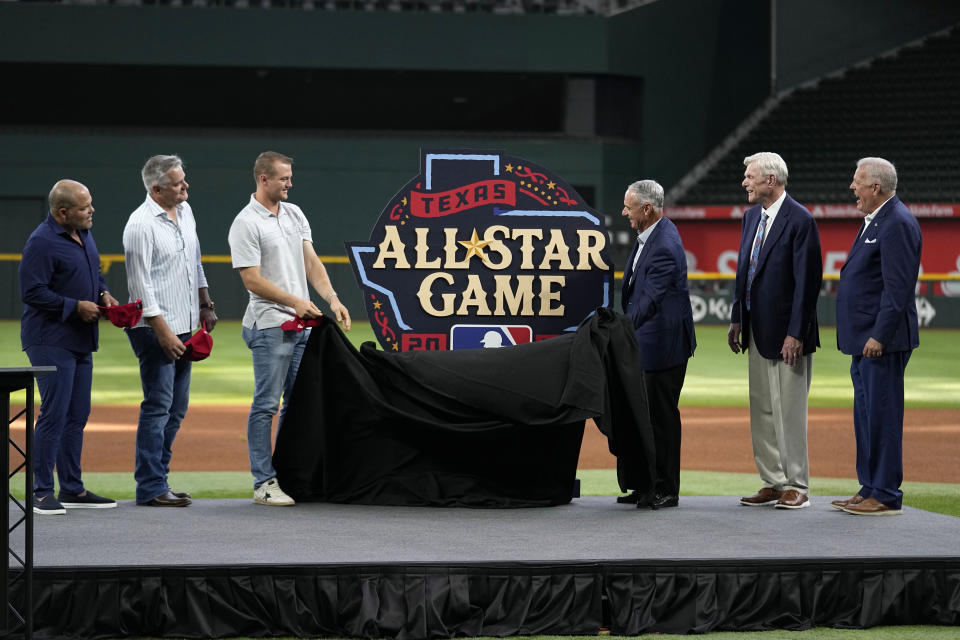 Former players Ivan "Pudge" Rodriguez, from left, Kenny Rogers, Texas Rangers third baseman Josh Jung, Major League Baseball Commissioner Rob Manfred, Rangers team owner Ray Davis and Arlington Mayor Jim Ross, right, unveil the 2024 All-Star baseball game logo, Thursday, July 20, 2023, in Arlington, Texas. The MLB All-Star Game has grown into a truly Texas-sized event since the last time the Rangers hosted the midsummer classic. The countdown is on for 2024 game on July 16, and all of the activities around the game. (AP Photo/Tony Gutierrez)